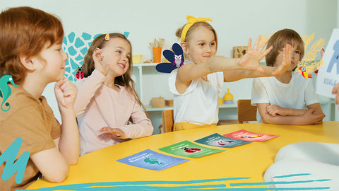 Kids in a classroom with representation of their Totem behind  them. There is Totem junior cards on the table in front of them. 